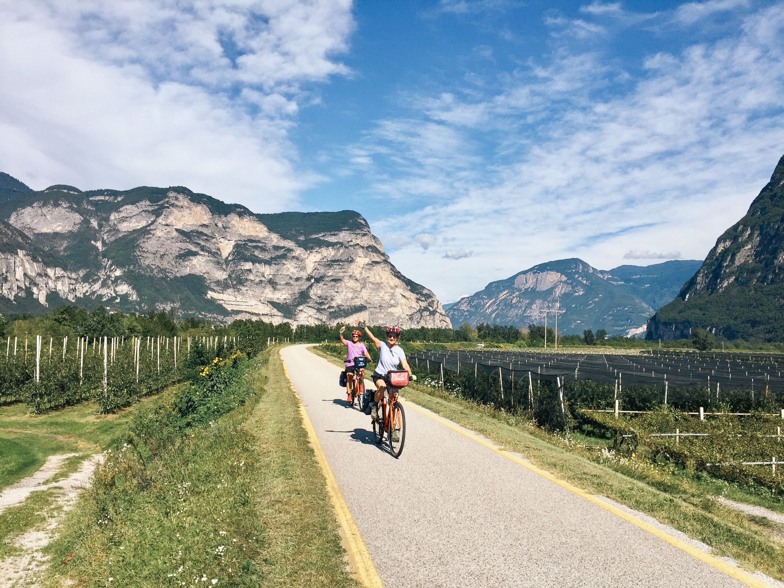 Radfahrer unterwegs auf dem Etschradweg zwischen Grün und Bergen im Hintergrund, Familienurlaub mit dem Rad